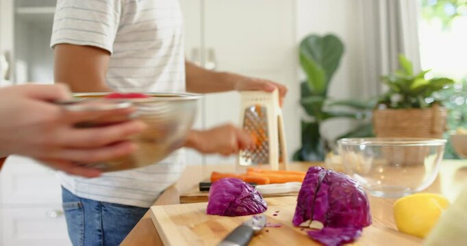 Chopping vegetables and grating carrots, family preparing meal together in kitchen