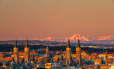 Zaragoza El Pilar con skyline de ciudad en el atardecer y montañas nevadas de fondo