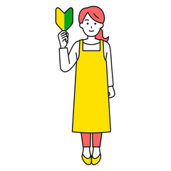 初心者マークを掲げるエプロン姿の女性（全身）