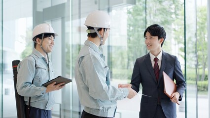 クライアントと打ち合わせをする作業服を着た男性
