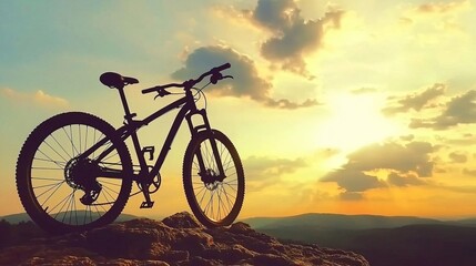 Obraz premium Bicycle Silhouette on Rocky Ledge at Sunset, Leisure rides inspire mountain bikers concept.
