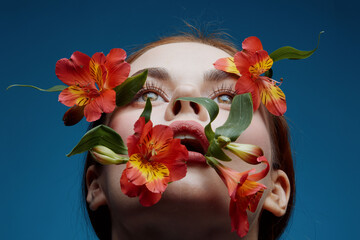 Woman with flowers, exhibiting serene emotions, against a blue backdrop, emphasizing beauty and...