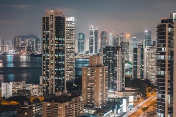 A nighttime cityscape of a modern urban skyline with tall skyscrapers and high-rise buildings