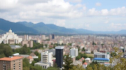 Obraz premium Blurry cityscape with distant mountains under a blue sky and scattered clouds