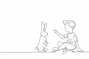 Single one line drawing the boy sitting cross legged and playing with rabbit. Train a rabbit to perform in the circus. Pets. National Kids and Pets Day. Continuous line design graphic illustration