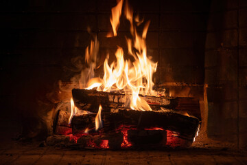 Fire burning in a fireplace, wood logs and flames. Warm home, heat. Christmas holiday