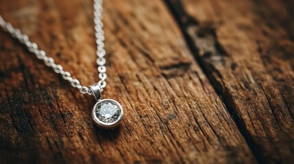 A silver thin necklace with a tiny diamond pendant, laid out on a rustic wooden table for a natural look.