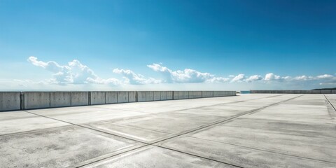 Empty concrete expanse with a low wall under a bright blue sky