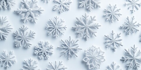Bright white flat lay composition of various snowflakes in soft white tones creating a festive atmosphere for Christmas and New Year celebrations.