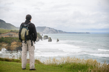 Man standing on clifftop and looking at the views of Three Sisters rock formation. Tongaporutu. Taranaki. New Zealand.