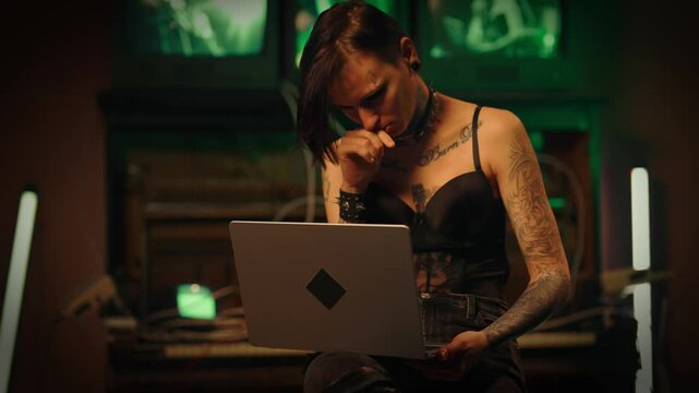 Hack attack and cyber security, tattooed woman hacker working with laptop. Portrait of talented IT professional programmer lady using portable computer for writing code and hacking website, cybercrime