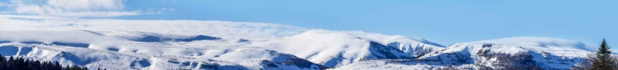 panoramic photo of the Lago Naki highlands in snow against the blue sky on a sunny winter day