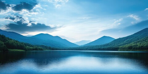 Fototapeta premium Serene blue mountainous landscape reflected in calm water under a twilight sky with soft clouds providing ample space for text at center