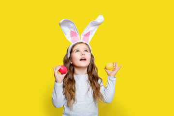 Cute little child girl wearing bunny ears on Easter day. Easter day. Girl with Easter eggs and live...