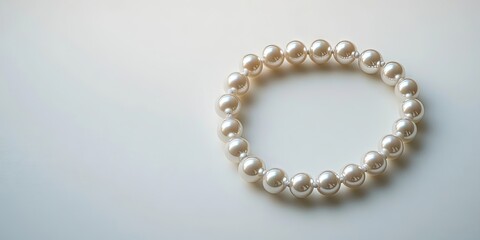 Elegant pearl necklace arranged in a circular formation on soft white background with ample negative space highlighting the pearls' luster.