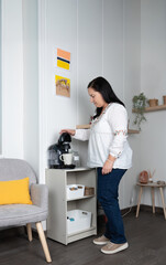 Mature woman preparing coffee in an organized corner of the home. Warm decoration with simple, functional and minimalist furniture