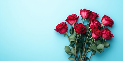 Red roses elegantly arranged in a bouquet against a soft blue background captured from a flat top view perspective ample space for text