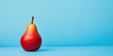 Ripe red delicious pear centered on a light blue background emphasizing organic food and zero waste aesthetics with soft shadows