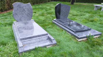 Tombstones grey black marble in the cemetery green grass