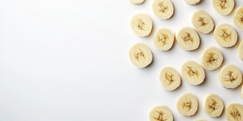 Obraz premium Banana slices arranged diagonally on a bright white background creating ample negative space for text or design elements on the right side