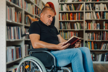 Man in wheelchair reading a book in library, enjoying literature and culture