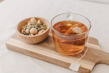 Set of mixed beans and hot tea on wooden plate.