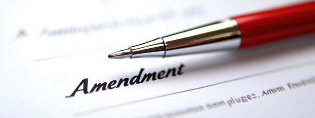 Close-up of a red pen poised over a document titled 'Amendment', symbolizing legal changes or modifications.