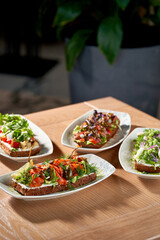 A delectable spread of four open-faced sandwiches, or smorrebrod, each with a unique and vibrant combination of toppings.