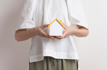 Woman with a miniature house. Thinking about the home, housework, household finances, loans,...