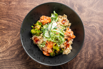 A vibrant bowl of quinoa topped with grilled salmon, fresh vegetables like broccoli and cucumber, drizzled with a savory sauce. Ideal for promoting healthy eating or gourmet cuisine.