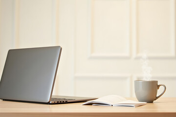 Fototapeta premium Office desk with a laptop, notebook, and coffee cup, clean and minimalist background