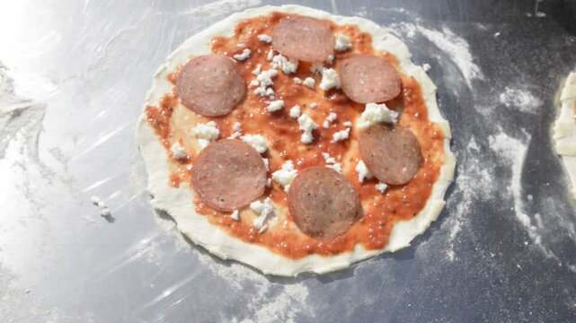 pizza italiana con salame fatta a mano sul bancone di acciaio all'aperto