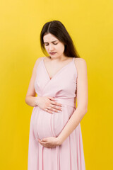 a pregnant girl who has a stomach ache stands on a colored background. isolated