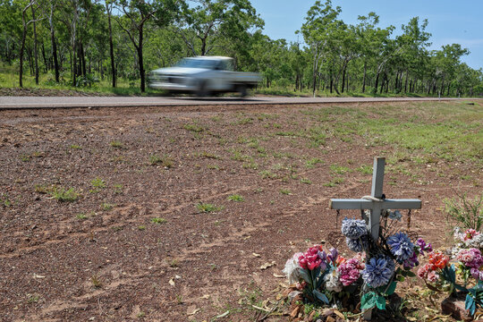 Cross next to road. Commemorate death of loved one, family, friend. Speeding pickup truck, ute, passing by. Road safety, death toll, statistics, fatal accident or crash, traffic