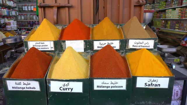 display of spices for cooking in the shape of a pyramid in a shop inside the souq of Marrakech, spices and flavors typical of Moroccan tjine cuisine, curry, cumin and paprika, safran 
