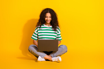 Full body portrait of nice young girl sit floor use laptop wear striped t-shirt isolated on yellow...