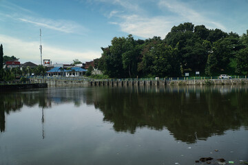 Fototapeta premium Scenic View of Tambakboyo Reservoir Surrounded by Trees and Clear Sky