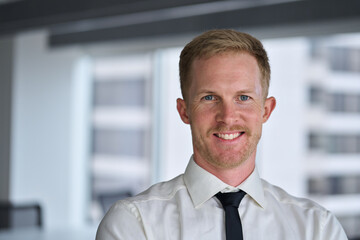 Fototapeta premium Portrait of young happy professional business man, smiling corporate leader in his 30s, confident businessman executive manager wearing white shirt and tie looking at camera in office. Headshot.