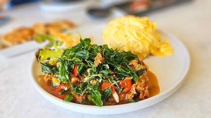 Stir-fried Holy Basil with Chicken and Omelette (Pad Ka Prao): A delectable Thai dish featuring stir-fried chicken with holy basil leaves, served alongside fluffy omelette and rice.