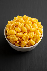 Homemade Dry Raw Gnocchi Pasta in a Bowl on a black background, side view.