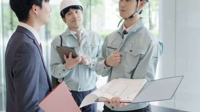 クライアントと打ち合わせをする作業服を着た男性