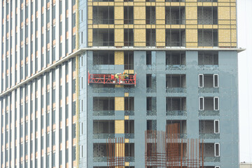 Suspended scaffolding for work on the facade of the building on a winter day