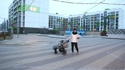 Woman with stroller explores empty urban square during early morning light