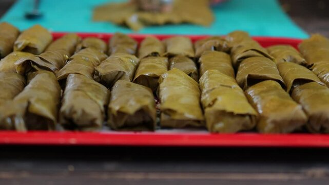 People cook dolma food.
Grape leaves stuffed with minced meat.