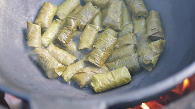 Vegetables, grape leaves stuffed with minced meat, are boiled and stewed in a cauldron and steam goes over them