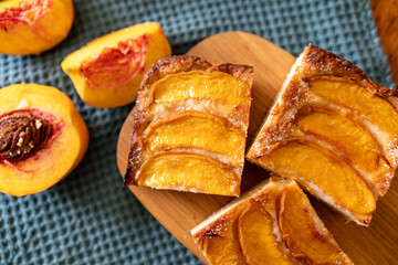 A dessert made of sliced peaches is on a wooden cutting board. The dessert is covered in sugar and looks delicious.