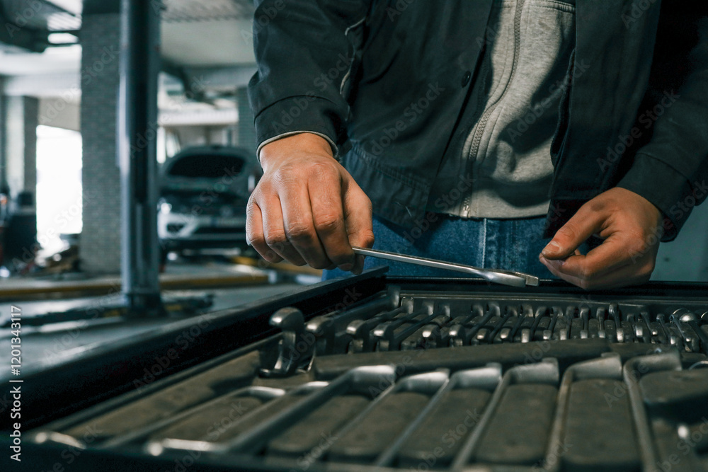 Poster Close-up of a mechanic's hand picking wrenches from a well-organized tool tray in a workshop. Metal wrenches in various sizes, ready for repair tasks