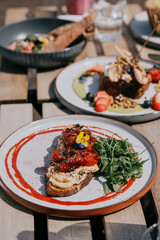 A plate of food with a red sauce and a green salad. The plate is on a wooden table