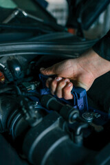 A mechanic's hand replacing a car battery in the engine compartment of a modern vehicle during maintenance. Detailed view of car components and professional work