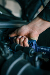 A mechanic's hand replacing a car battery in the engine compartment of a modern vehicle during maintenance. Detailed view of car components and professional work